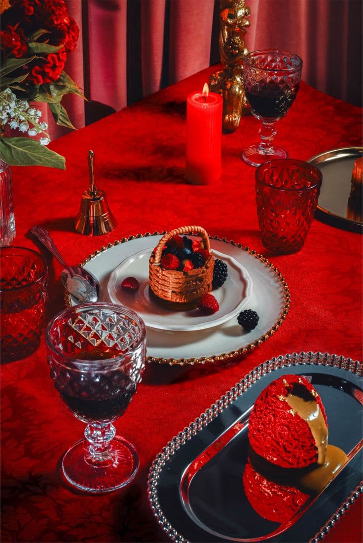 Mesa de banquete roja con copas talladas y una vela