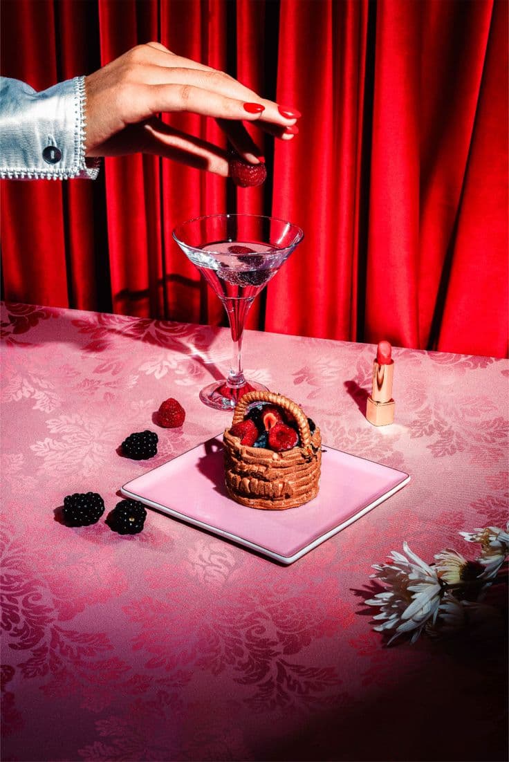 Martini y pastelito de frutos rojos sobre mantel rosa